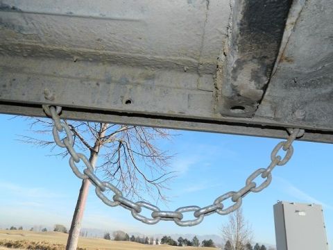 1979 Ford Bronco - A chain is attached to the undercarriage of a vehicle, with a tree and sky visible through the opening.