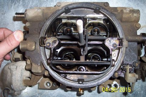 1973 Ford F-250 - A hand is shown on the side of a greasy carburetor, revealing its internal components.