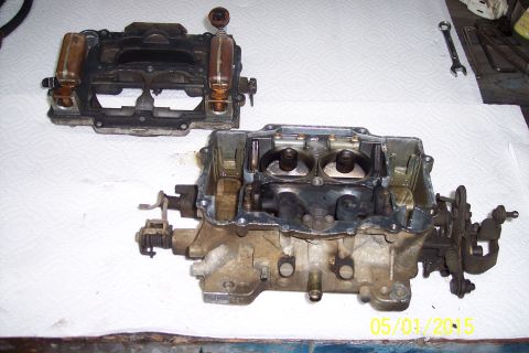 1973 Ford F-250 - A disassembled carburetor, likely for an older vehicle, is laid out on a white surface with tools nearby.