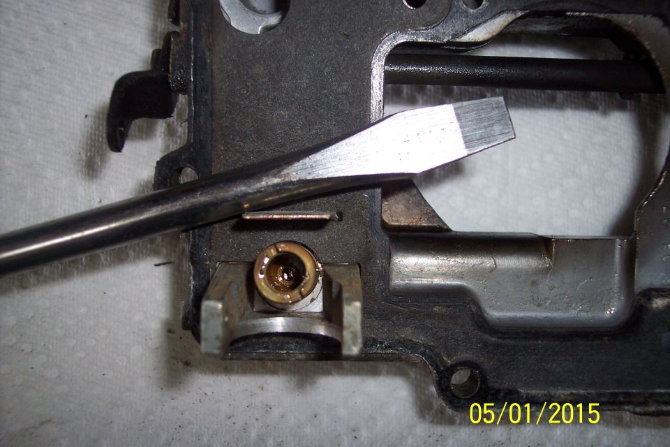 Close-up of a carburetor component with a flathead screwdriver tip inserted