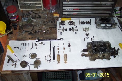 1973 Ford F-250 - Various carburetor parts and tools are organized on a white paper towel covering a wooden surface.