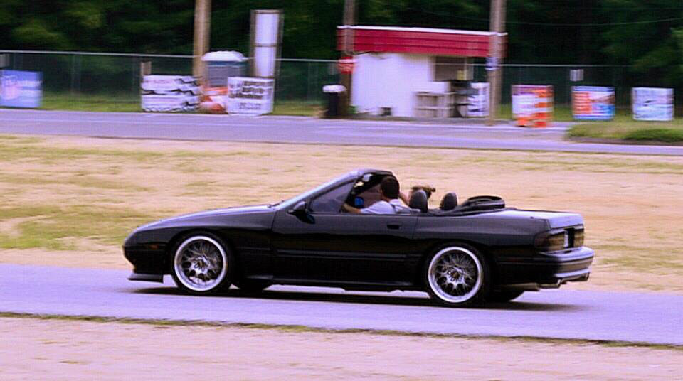 Black convertible sports car with aftermarket wheels on a track