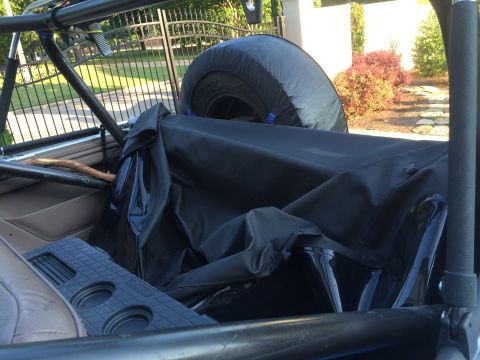 1996 Ford Bronco - The interior of a soft top vehicle is visible, with a spare tire mounted and the top folded down.