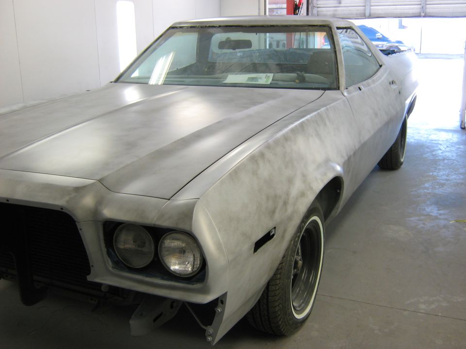 Unpainted car body, front 3/4 view, showing dual headlights and a prominent hood crease