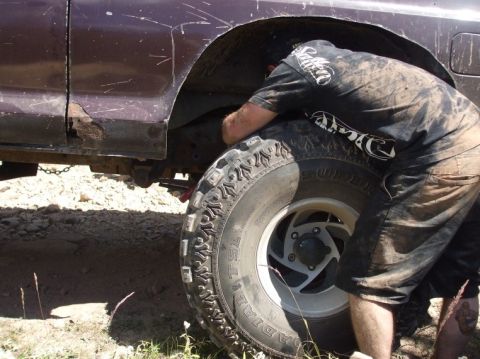 1979 Ford Bronco - Someone is working on the wheel well of a dirty SUV, showing rust damage.