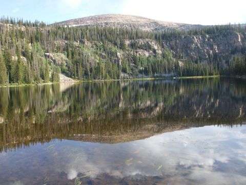 1979 Ford Bronco - A mountain lake reflects the surrounding pine-covered slopes and a clear sky.