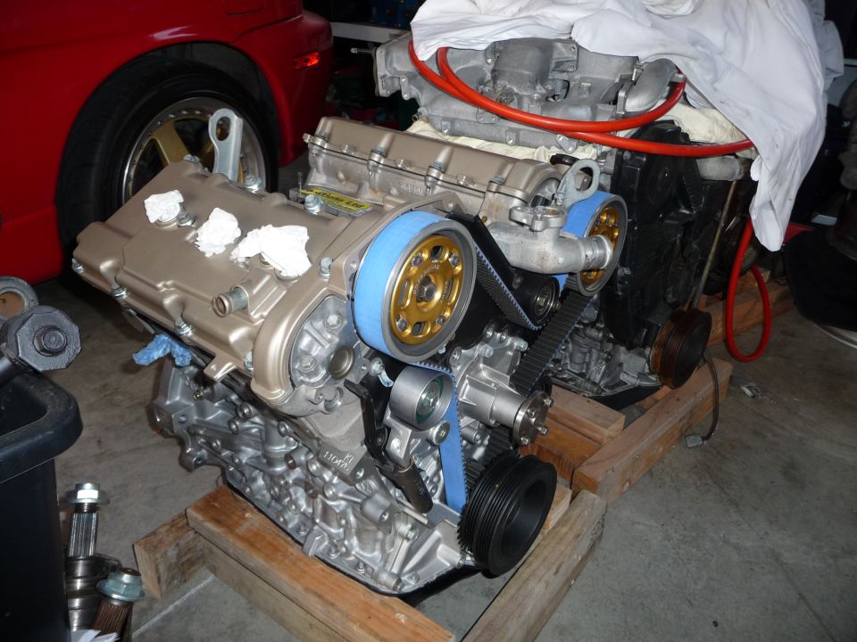 Engine with blue timing belt and gold pulleys on wooden stand