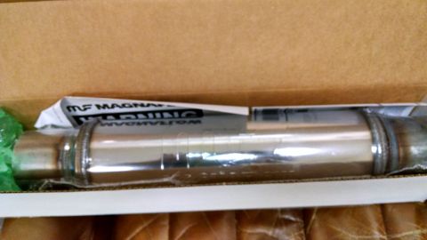 Chrome exhaust muffler in a cardboard box, with "MF MAGNAFLOW WARNING" text visible
