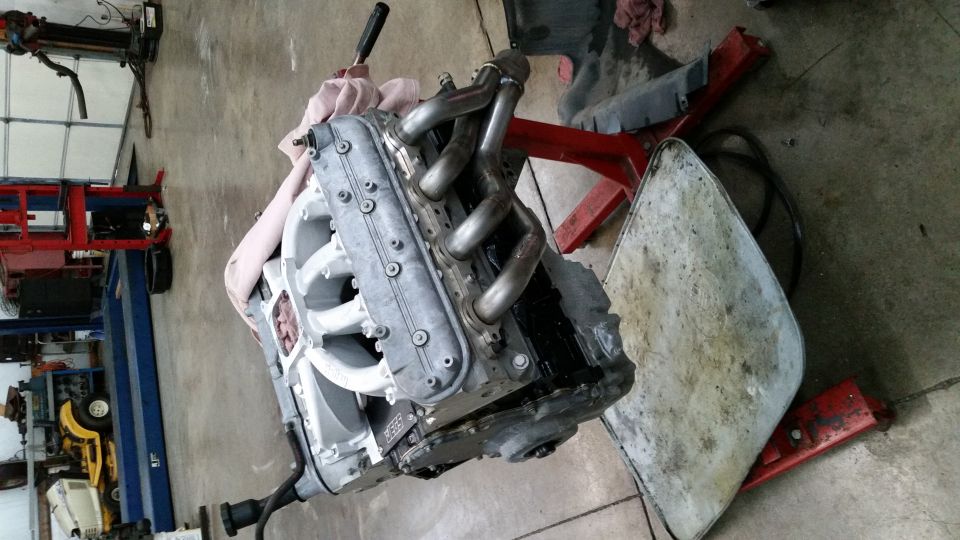 LS engine with headers on an engine stand in a garage