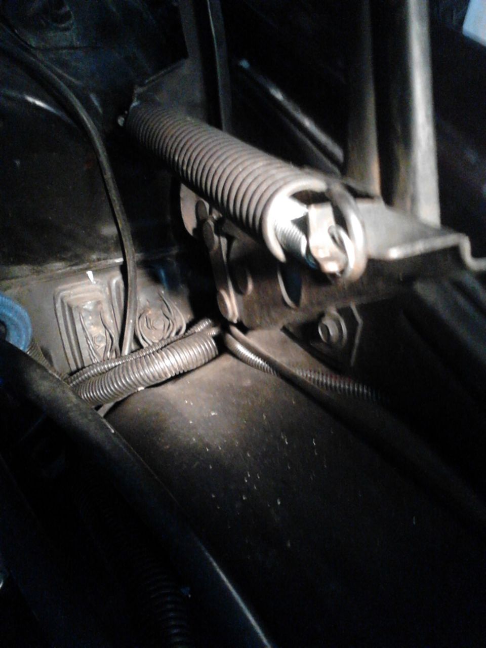 Close-up of a car's hood latch mechanism with a spring