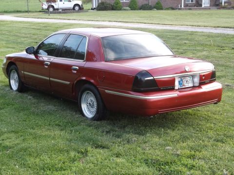 1999 Mercury Grand Marquis - This red sedan, likely a 2003 model, is shown from the rear 3/4 angle.