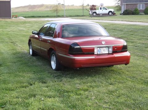 1999 Mercury Grand Marquis - Rear view of a red 1999 Mercury Grand Marquis parked on a grassy lawn.