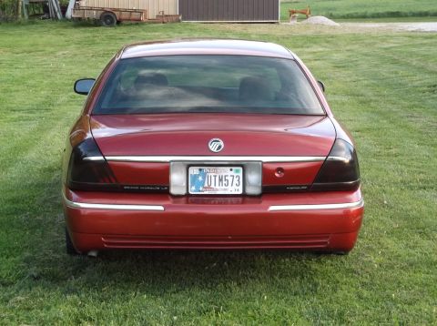 1999 Mercury Grand Marquis - Rear view of a red 1999 Mercury Grand Marquis, showing its distinctive taillights and license plate.