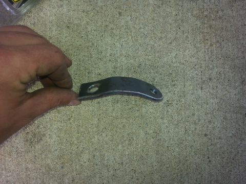 1996 Ford Bronco - A metal bracket with two mounting holes is shown, held by a hand against a concrete surface.