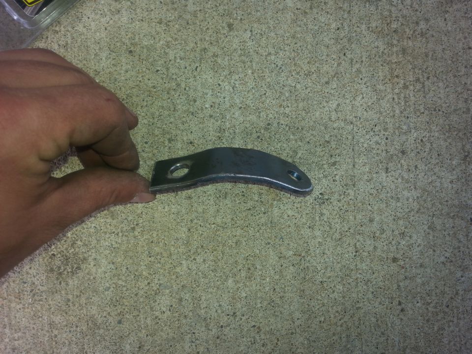 Curved metal bracket with two holes, held by a hand