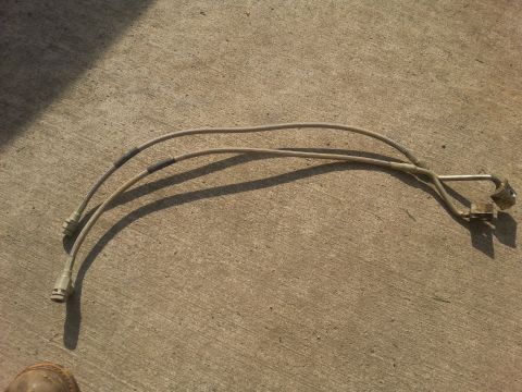 1996 Ford Bronco - A pair of brake lines lie on a concrete surface, casting shadows.