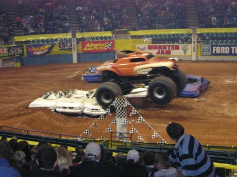 1996 Ford Bronco - A monster truck performs a jump over several wrecked cars during a Monster Jam event.