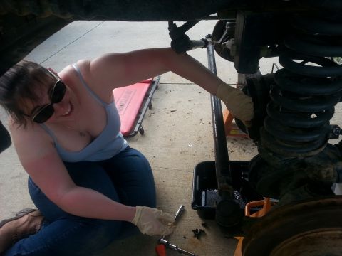 1996 Ford Bronco - A person works on the suspension of a vehicle, with tools and a drain pan visible.