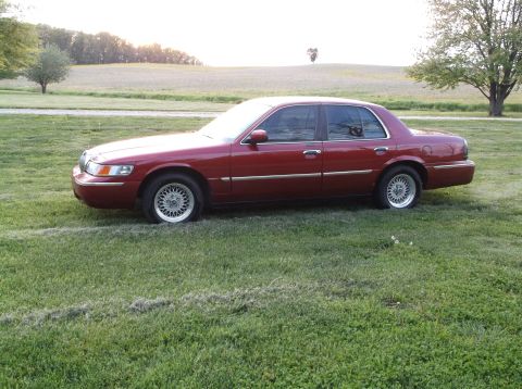 1999 Mercury Grand Marquis - Maroon 1999 Mercury Grand Marquis sedan sits on a grassy field during the day.