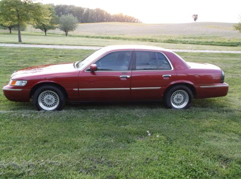 1999 Mercury Grand Marquis - This 1999 Mercury Grand Marquis is seen from the side, parked on a grassy field during the day.