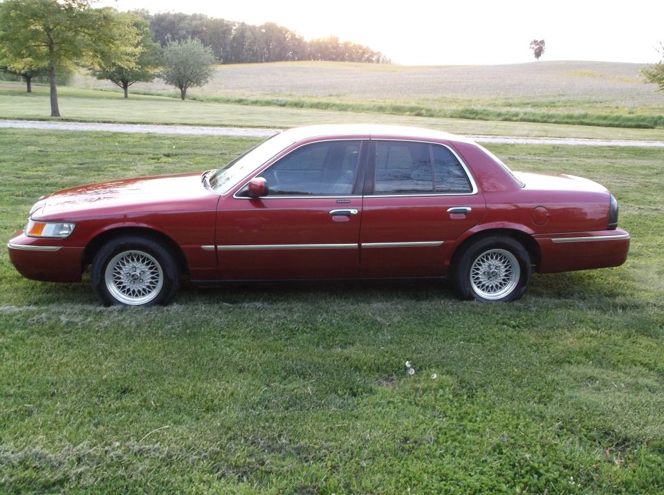 Red 1999 Mercury Grand Marquis sedan, side view, parked on grass