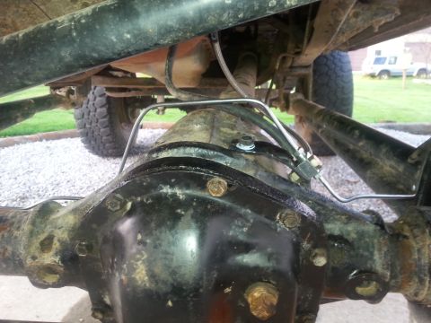 1996 Ford Bronco - Undercarriage view of a vehicle's rear axle and suspension system, with another vehicle in the distance.