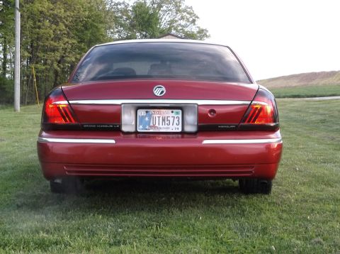 1999 Mercury Grand Marquis - Rear view of a red 1999 Mercury Grand Marquis, showing its distinctive taillights and license plate.