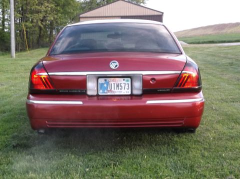 1999 Mercury Grand Marquis - The rear of a red Mercury Grand Marquis is shown, its taillights, license plate, and chrome trim.
