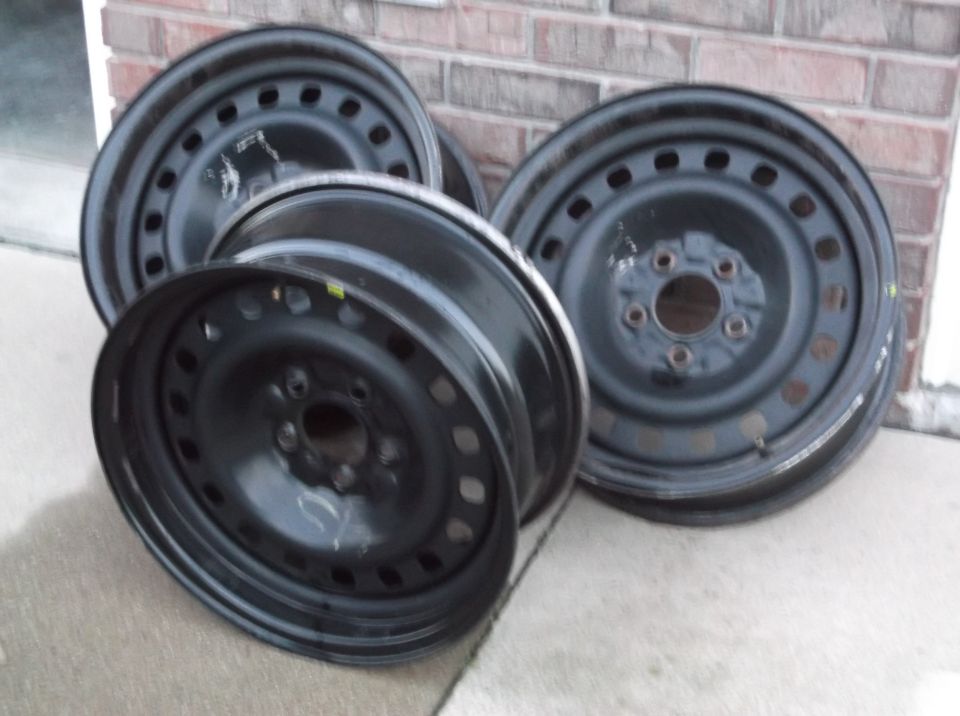 Four black steel wheels stacked on concrete