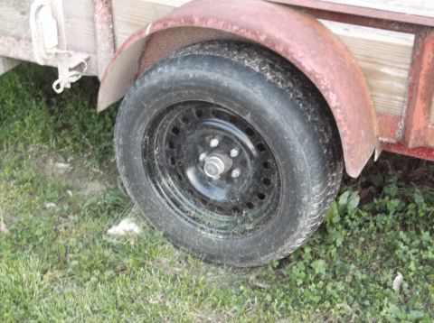 1999 Mercury Grand Marquis - Close-up of a trailer wheel and fender, showing wear and tear.