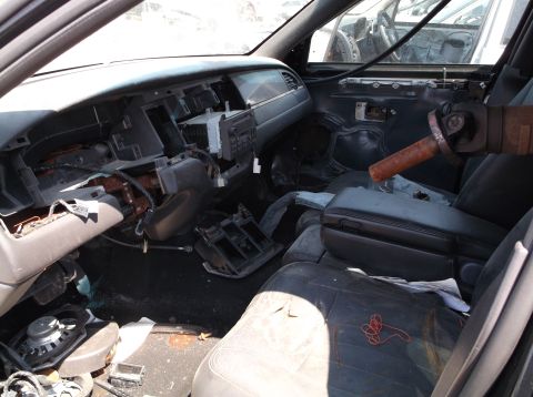 1999 Mercury Grand Marquis - The interior of a 1999 Mercury Grand Marquis shows significant damage and missing parts, indicating it is likely from a junkyard.