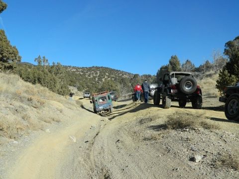 1979 Ford Bronco - Off-road vehicles traverse a challenging dirt trail in a hilly, arid landscape.