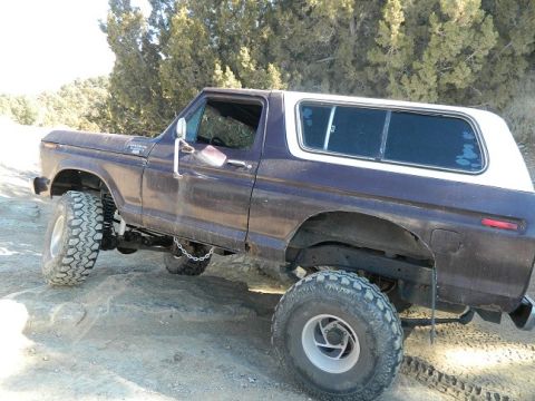 1979 Ford Bronco - This lifted Ford Bronco navigates a rocky trail, showing its off-road modifications.