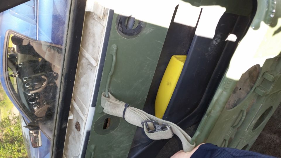 Vehicle interior with green paneling, a yellow object, and a strap. A hand is visible