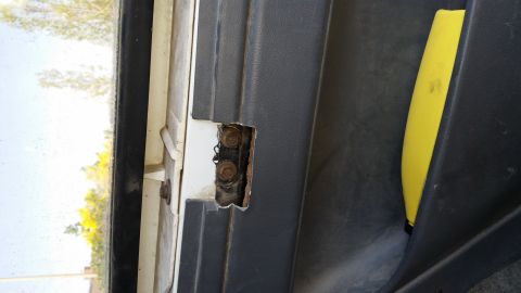 1993 Ford Bronco - Close-up view of a vehicle's interior door hinge mechanism, showing wear and tear.