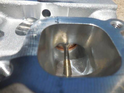 1979 Ford Bronco - A detailed view of a cylinder head's intake port, the valve and its stem within the polished aluminum casting.
