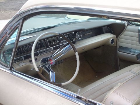 2004 Ford Crown Victoria - The interior of a vintage car shows a beige dashboard and seats, with a two-tone steering wheel and a watermark at the bottom right.