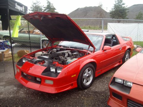 2004 Ford Crown Victoria - A red sports car with its hood open is displayed, with another red car partially visible in the foreground.