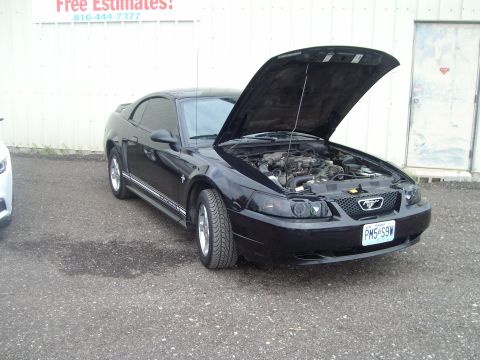 2004 Ford Crown Victoria - Black Ford Mustang with its hood open, revealing the engine compartment. The vehicle is parked outdoors in front of a building.