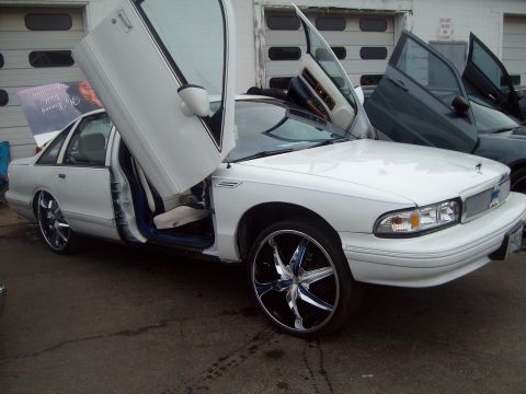 2004 Ford Crown Victoria - A white sedan with its doors open, parked next to another vehicle.