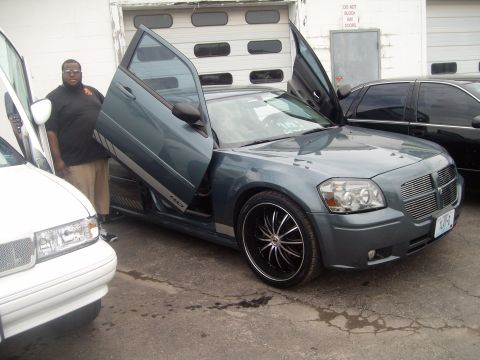 2004 Ford Crown Victoria - A gray Dodge Magnum is shown with its lambo doors open, parked next to a white vehicle.
