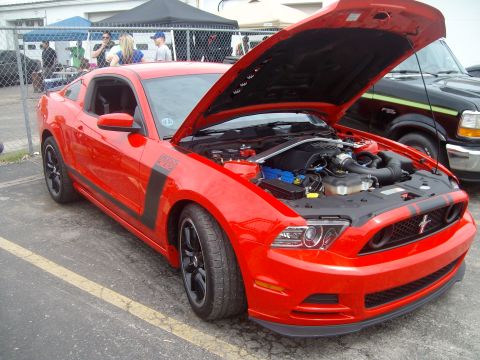 2004 Ford Crown Victoria - A red 2012 Ford Mustang Boss 302 is displayed with its hood open, revealing the engine compartment and distinctive side stripes.