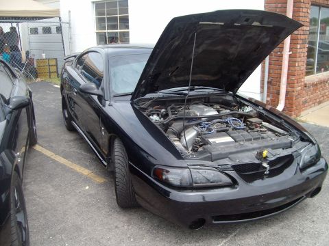 2004 Ford Crown Victoria - A black Ford Mustang is parked outside with its hood open, displaying the engine compartment.