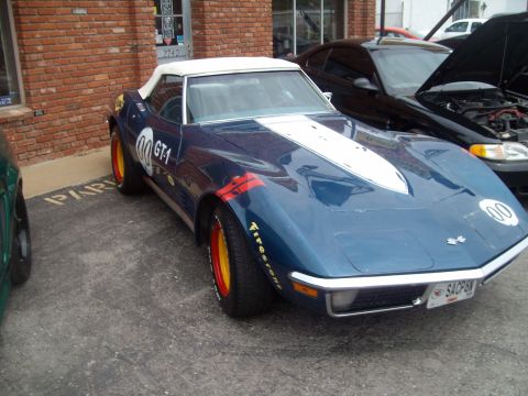 2004 Ford Crown Victoria - A blue convertible race car with GT-1 markings is parked next to a black car.