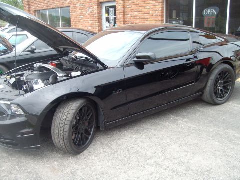 2004 Ford Crown Victoria - A black coupe is parked outside a building with its hood open, revealing the engine compartment.