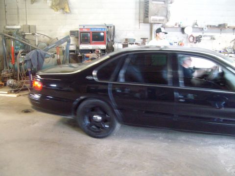 2004 Ford Crown Victoria - A black sedan is parked inside a garage, with a dyno machine visible in the background.