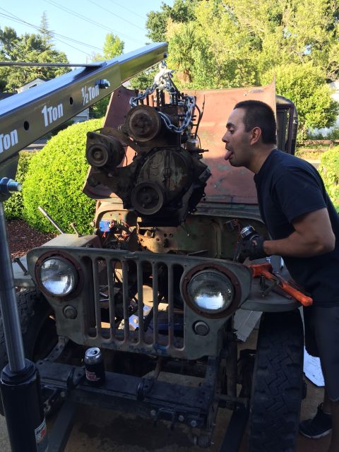 1946 Jeep Willys - A man works on removing the engine from a vintage Jeep, with a crane assisting the lift.