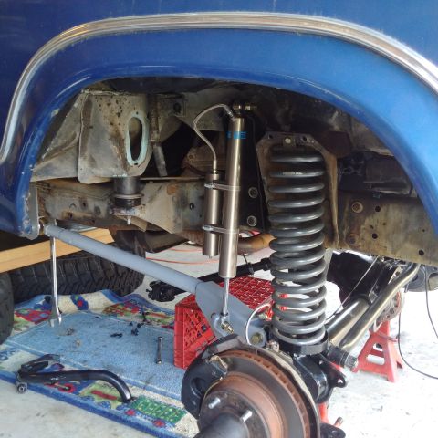 1978 Ford Bronco - Close-up of the suspension system of a blue 1978 Ford Bronco, showing upgraded shocks and springs.