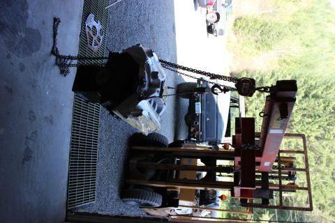 1979 Ford Bronco - An engine and transmission are being lifted out of a vehicle using a chain hoist and engine crane.