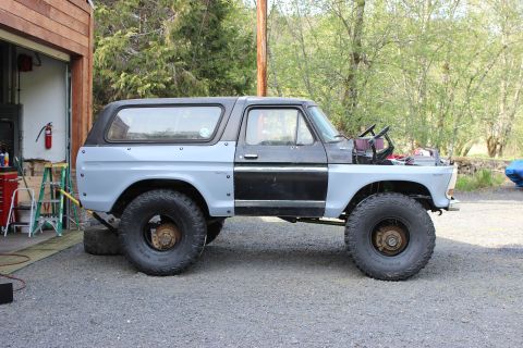 1979 Ford Bronco - Ford Bronco undergoing restoration, showing primer gray body panels and large off-road tires.